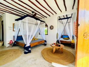 Habitación con 2 camas y mesa. en Kameleon Blue en Kizimkazi