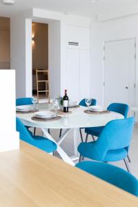 a dining room with a white table and blue chairs at Modern apartment in the center of St Julians in St. Julianʼs