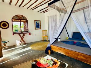 a bedroom with a bed with a mosquito net at Kameleon Blue in Kizimkazi
