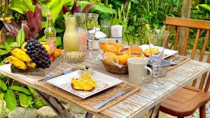 - une table en bois avec des fruits et des assiettes de nourriture dans l'établissement Canto do Jão, à Parati