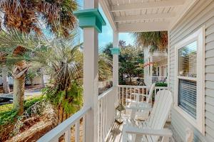 a porch with white chairs and a palm tree at Serenity Now in Santa Rosa Beach