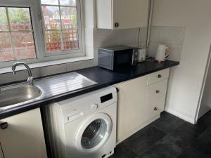 a kitchen with a washing machine and a microwave at A nice double size bedroom in Mottingham in Eltham