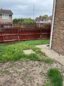 un patio con una valla de madera y césped en A nice double size bedroom in Mottingham en Eltham