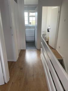 a bathroom with white walls and a wooden floor at A nice double size bedroom in Mottingham in Eltham