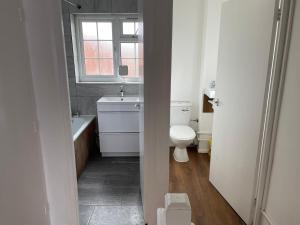 a bathroom with a toilet and a sink and a window at A nice double size bedroom in Mottingham in Eltham