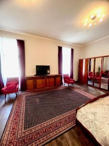 a bedroom with a bed and a television and red chairs at Appartements in Wienerwald Residenz in Baden