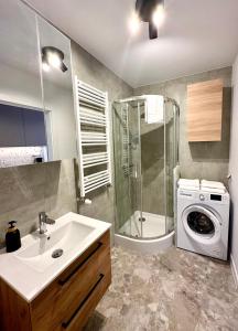 a bathroom with a sink and a washing machine at Platon Residence Apartments in Łódź