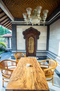 a wooden table with chairs and a chandelier at Bali Culture Guesthouse in Ubud