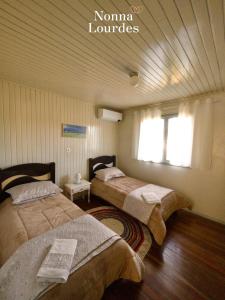 a bedroom with two beds and a window at Recanto Nonna Lourdes - Vale dos Vinhedos in Bento Gonçalves