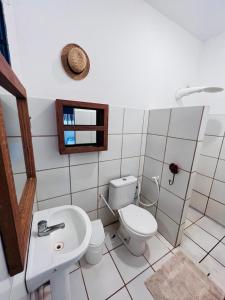 a white bathroom with a toilet and a sink at Casa da Madame in São Miguel do Gostoso