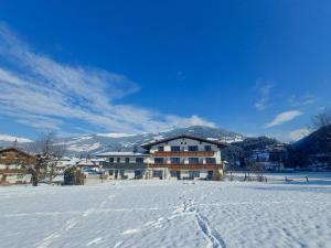 a building in the snow with footprints in the snow at Alpenzeit Zillertal Apartments in Zell am Ziller