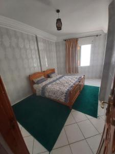 a bedroom with a bed and a green rug at Résidence Taghazout Oufella by Surf Times in Taghazout