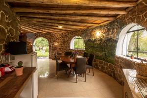 eine Küche mit einem Tisch und einer Steinmauer in der Unterkunft Bungalow RURU WASI in Urubamba