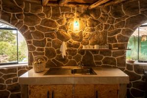 a stone kitchen with a sink and a stone wall at Bungalow RURU WASI in Urubamba