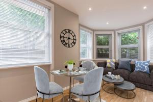 ein Wohnzimmer mit einem Sofa, einem Tisch und Stühlen in der Unterkunft Kensington Olympia Apartment, Breakfast in London