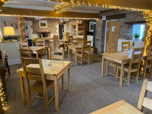 un restaurante con mesas de madera, sillas y luces en The Temple Bar Inn en Hereford