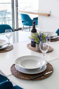 una mesa blanca con platos y copas de vino. en Modern apartment in the center of St Julians, en San Julián