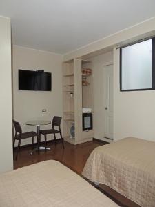 a bedroom with a bed and a table and a tv at San Miguel Awanka Hotel in Lima