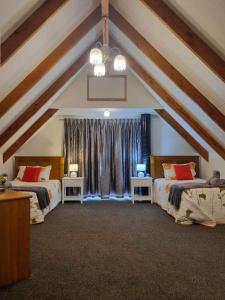 Cette chambre mansardée comprend 2 lits et une fenêtre. dans l'établissement Westholm Lodge, à Harihari