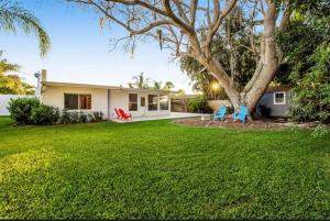 a house with a yard with two chairs and a tree at Tropical Shores Retreat-10 Min to Siesta Key Beach in Sarasota