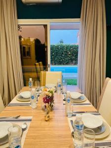 a wooden table with plates and glasses and flowers on it at Villa Kimia Elfeige in Marrakesh