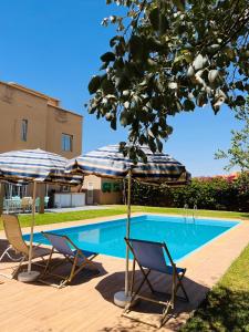 two chairs and umbrellas next to a swimming pool at Villa Kimia Elfeige in Marrakesh