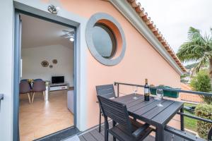 a patio with a wooden table and chairs on a balcony at Sara House in Ponta do Sol