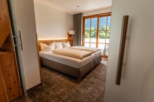 Habitación de hotel con cama y ventana en ARNIKA Garni en Oberammergau