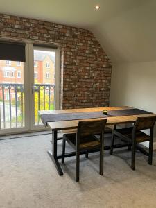 een eettafel met 2 stoelen en een bakstenen muur bij Spacious Apartment NEC BHX in Solihull