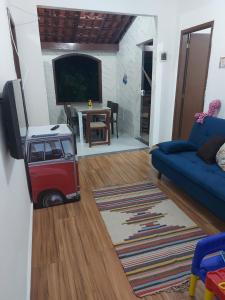 ein Wohnzimmer mit einem TV und einem blauen Sofa in der Unterkunft Aconchego do Bem-te-vi 2 qtos 60m2 Praia Grande in Arraial do Cabo
