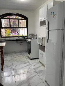 uma cozinha com um frigorífico branco e uma janela em Castelinho da Paz em Itanhaém
