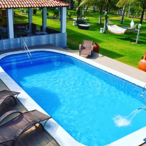 a large swimming pool with two chairs and a yard at Chalé em Maragogi in Maragogi