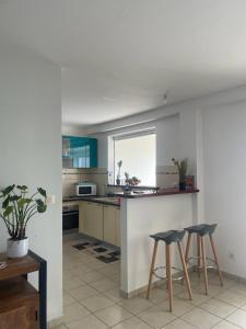 a kitchen with two bar stools and a counter at Les terrasses de la Marina in Le Marin