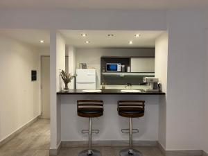 a kitchen with two bar stools at a counter at Madero City Buenos Aires in Buenos Aires