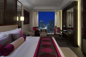 a bedroom with a large bed with a desk and a room with a view at Taj Dubai in Dubai