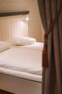 um par de camas com lençóis brancos e almofadas em Viö Gården em Karlskrona