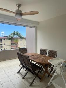 a dining room table with chairs and a ceiling fan at Les terrasses de la Marina in Le Marin