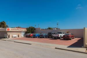 a parking lot with cars parked in front of a building at Juanedu Suites in Oranjestad