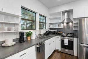 una cocina con armarios blancos y electrodomésticos de acero inoxidable en Chic Comforts in Tobin. en San Antonio