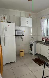 a kitchen with a white refrigerator and a stove at Apartamento Em Balneário Mogiano in Bertioga
