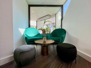a room with two green chairs and a table and chairs at Best Western Voiron Centre in Voiron
