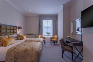 a hotel room with two beds and a desk at Oatlands Park Hotel in Weybridge