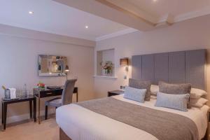 a hotel room with a large bed and a desk at Oatlands Park Hotel in Weybridge