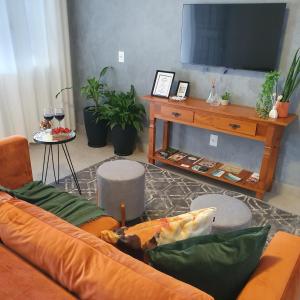 a living room with a couch and a television at Casa Romão 2 Pertinho de Vinícola e Centro in Espirito Santo Do Pinhal
