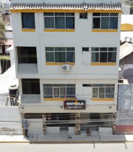 a tall white building with a sign on it at Hostal Resident in Piura