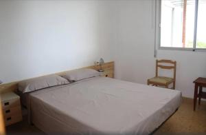 1 dormitorio con 1 cama, 1 silla y 1 ventana en Apartamento 1ª linea de mar, en Sant Carles de la Ràpita