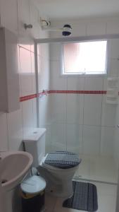 a white bathroom with a toilet and a sink at Apartamento Em Balneário Mogiano in Bertioga