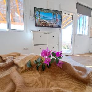 La Pérgola Calma في سان بارتولومي: غرفة نوم مع سرير مع زهور أرجوانية عليه