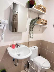 a bathroom with a sink and a toilet and a mirror at CELANDINE Residence by DMCI in Manila