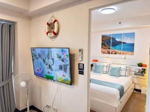 a bedroom with a bed and a flat screen tv at CELANDINE Residence by DMCI in Manila